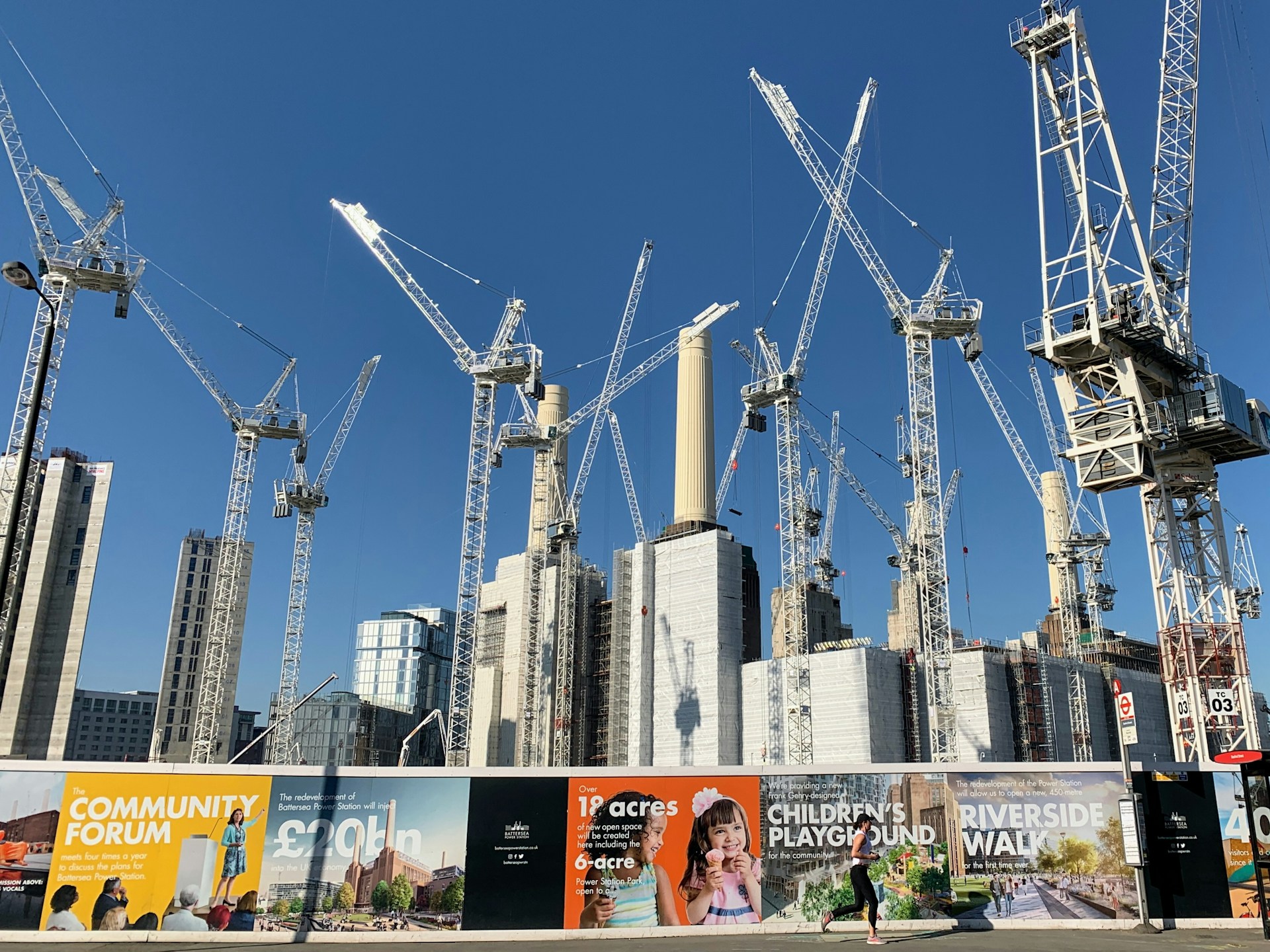 Cranes over a colourful hoarding, blue sky behind